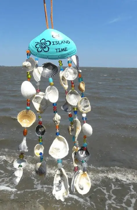 Shell wind chime featuring colorful beads and a blue top labeled "ISLAND TIME," hanging against a backdrop of ocean waves, relevant to the Arts and Crafts event at Gulf Waters Beach Front RV Resort.
