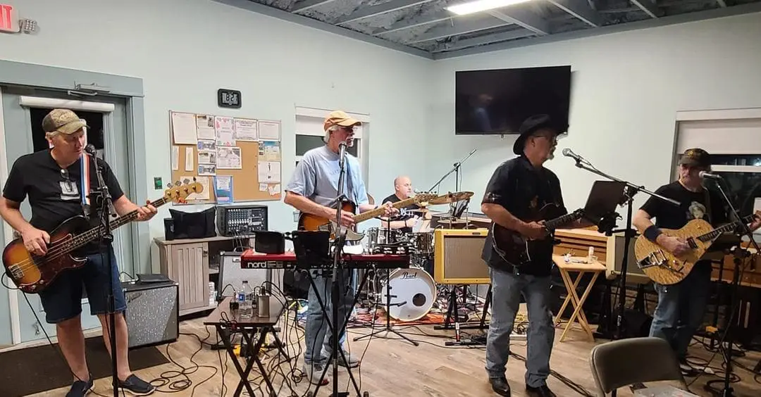 Live band performance at Gulf Waters Activity Center featuring The Free Beer Band, playing instruments with a casual setting and audience participation encouraged.