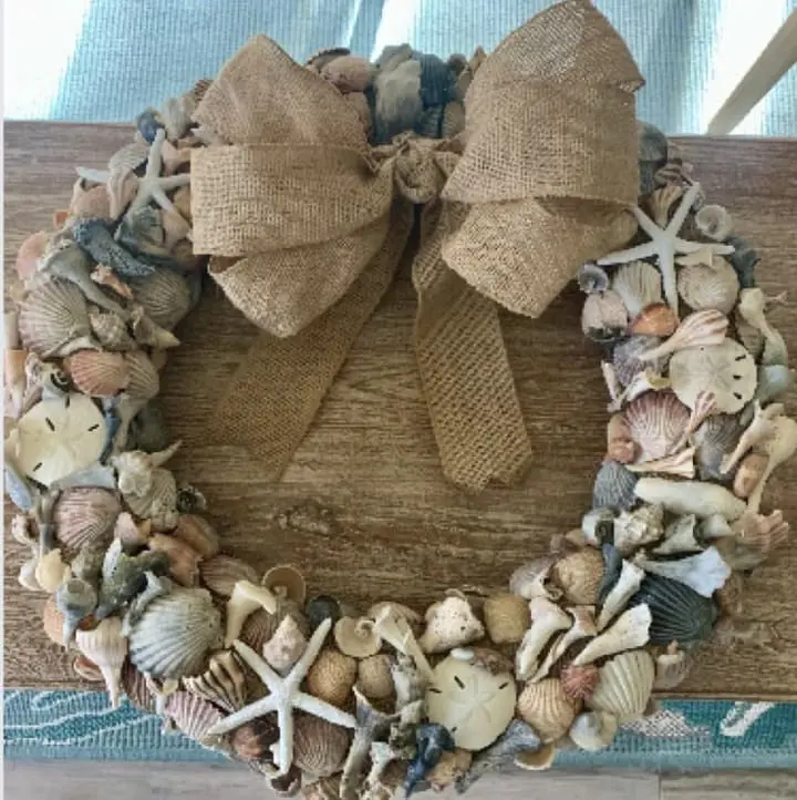 Shell wreath adorned with various seashells and a burlap bow, representing the creative project for the Arts & Crafts: Shell Wreaths event at Gulf Waters Beach Front RV Resort.