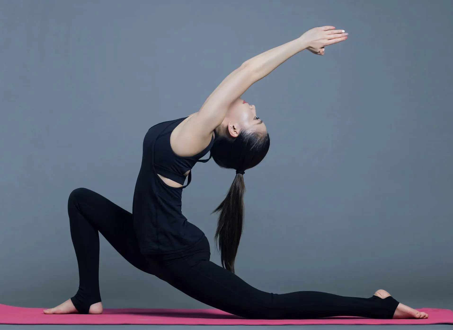 Woman practicing yoga in a lunge position on a pink mat, promoting wellness at Gulf Waters Beach Front RV Resort yoga sessions.