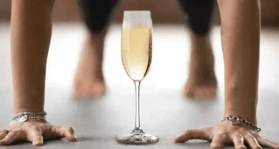 Person performing a push-up with a glass of Prosecco on the mat, symbolizing the Pilates & Prosecco event at Gulf Waters RV Resort.