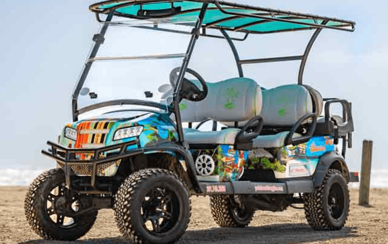 Golf cart with colorful design parked on sandy beach, promoting Gulf Waters RV Resort's rental services for exploring Port Aransas.