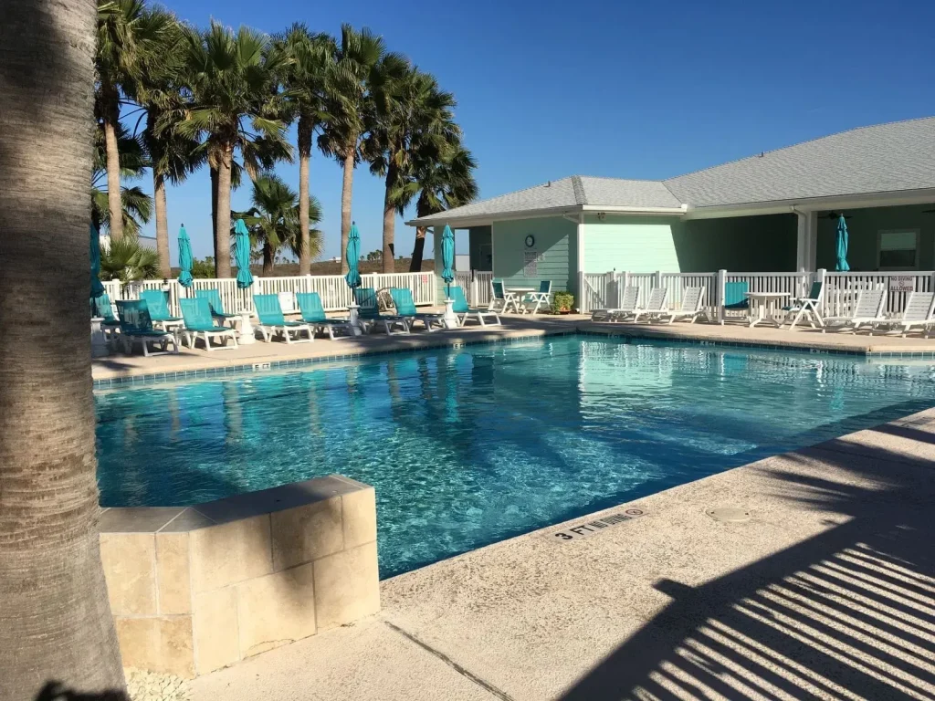 Community clubhouse and heated pool at Gulf Waters RV Resort with families enjoying amenities