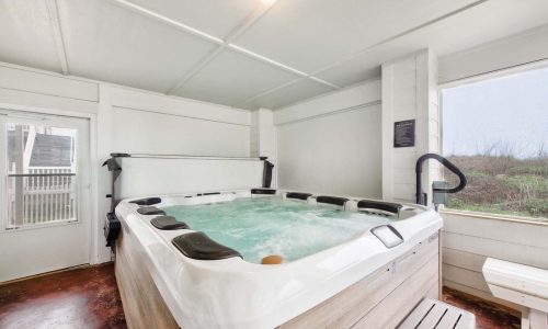 Indoor hot tub in a beach house at Gulf Waters Beach Front RV Resort, featuring a spacious design and large windows showcasing the coastal view.