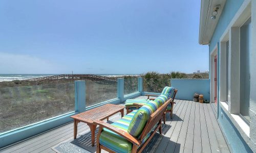 Beach house patio with colorful seating overlooking the ocean and nearby boardwalk at Gulf Waters Beach Front RV Resort.