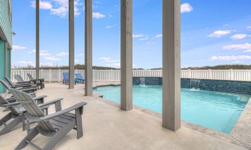 Poolside view with lounge chairs at Gulf Waters Beach Front RV Resort, featuring a private swimming pool and coastal scenery, ideal for beach house rentals on Mustang Island.