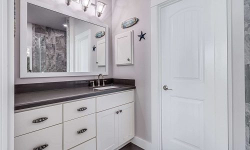 Modern bathroom interior with white cabinetry, mirror, and coastal decor, showcasing amenities available in beach house rentals at Gulf Waters RV Resort.