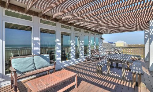 Private beach house patio with modern furniture, ocean view, and shaded seating area at Gulf Waters Beach Front RV Resort.