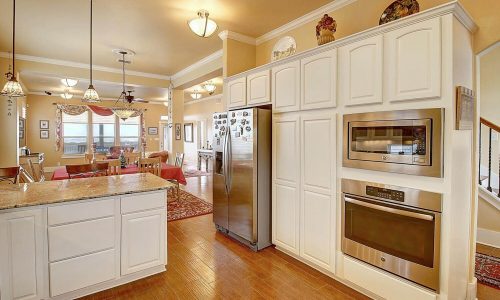 Modern kitchen with stainless steel appliances, granite countertops, and an open layout leading to a dining area, showcasing the inviting atmosphere of a beach house at Gulf Waters Beach Front RV Resort.