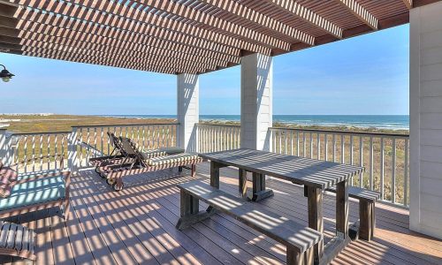 Beach house patio with seating and dining area overlooking Mustang Island's sandy shores at Gulf Waters Beach Front RV Resort.