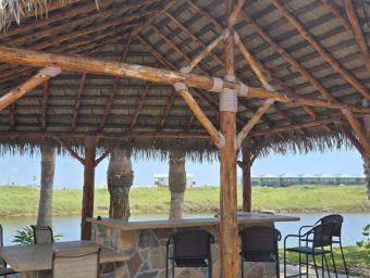 Beachfront shelter at Gulf Waters RV Resort with seating and palm trees.