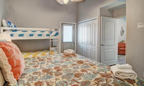 Cozy beach house interior featuring a floral-patterned bedspread, bunk beds, and a bright, inviting atmosphere, highlighting the modern comforts available at Gulf Waters Beach Front RV Resort.