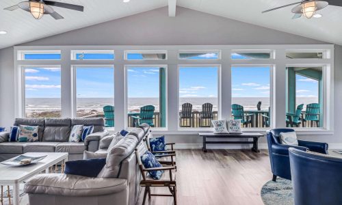 Spacious beach house interior with panoramic windows showcasing ocean views, modern furnishings, and comfortable seating, reflecting Gulf Waters RV Resort's coastal vacation experience.