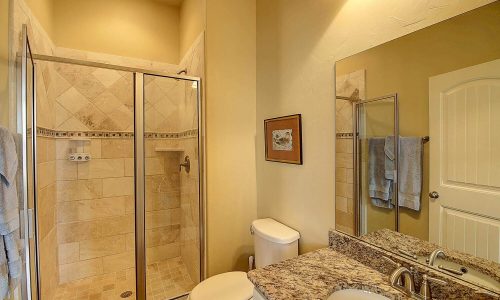 Modern bathroom with glass shower enclosure, granite countertop, and neutral-colored walls, showcasing amenities for a beach house rental at Gulf Waters Beach Front RV Resort.