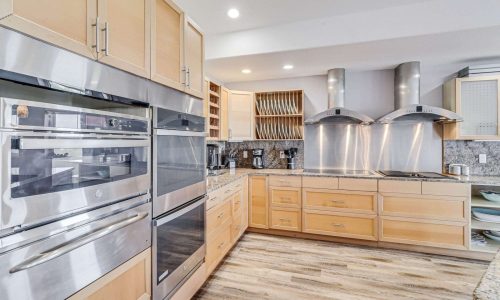 Modern kitchen interior with stainless steel appliances, wood cabinetry, and a spacious layout, ideal for preparing meals during a beach vacation at Gulf Waters Beach Front RV Resort.