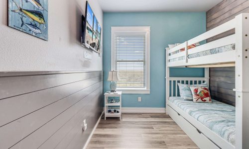 Cozy beach-themed bedroom with bunk beds, light blue walls, and nautical decor, showcasing a comfortable space for families at Gulf Waters Beach Front RV Resort.