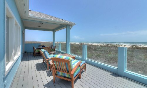 Beach house patio overlooking Mustang Island's sandy shores, featuring colorful seating and coastal views, ideal for a relaxing getaway at Gulf Waters Beach Front RV Resort.