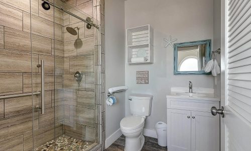 Modern beach house bathroom featuring a glass shower, stylish tile, and coastal decor, enhancing the vacation experience at Gulf Waters Beach Front RV Resort.