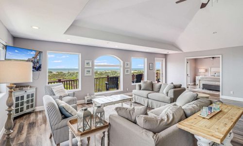 Spacious living room in a beach house at Gulf Waters Beach Front RV Resort, featuring modern furnishings, large windows with ocean views, and a cozy atmosphere, ideal for family vacations or group retreats.