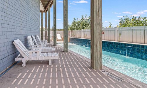 Private beach house poolside area with white lounge chairs and a sparkling blue pool at Gulf Waters Beach Front RV Resort, ideal for family vacations and group retreats near Mustang Island.