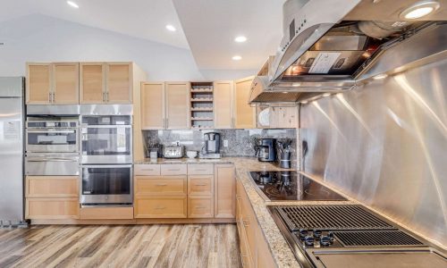 Modern kitchen with stainless steel appliances, granite countertops, and wooden cabinetry in a beach house at Gulf Waters Beach Front RV Resort.