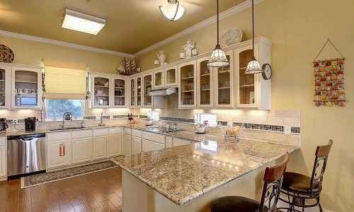 Modern kitchen interior with granite countertops, wooden flooring, and ample cabinetry, showcasing a bright and inviting space in a beach house at Gulf Waters Beach Front RV Resort.