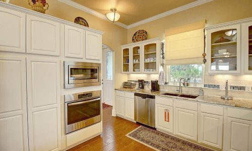 Modern kitchen interior featuring white cabinetry, stainless steel appliances, and granite countertops, designed for comfort and convenience in a beach house at Gulf Waters Beach Front RV Resort.