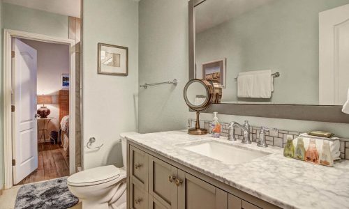 Modern bathroom interior with a marble countertop, sink, and mirror, featuring a doorway leading to a bedroom, emphasizing comfort and style for beach house rentals at Gulf Waters RV Resort.