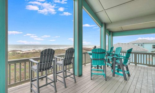 Beach house deck overlooking Mustang Island with turquoise and black bar stools, offering scenic ocean views and a relaxing coastal atmosphere.