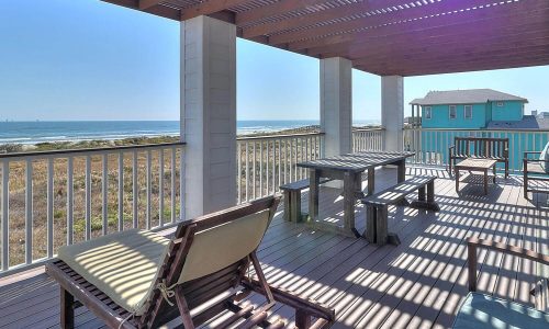 Cozy outdoor deck of a beach house at Gulf Waters Beach Front RV Resort, featuring seating and a table with ocean views, ideal for relaxing near Mustang Island's sandy shores.