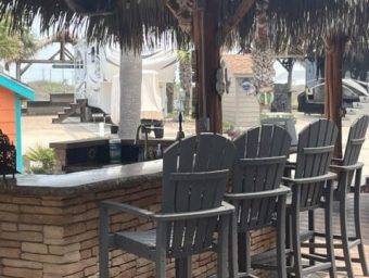 Beachfront bar with thatched roof and bar stools at Gulf Waters RV Resort.