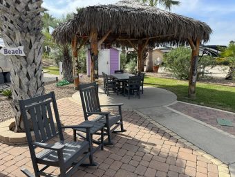 Beachfront RV resort outdoor seating area with rocking chairs and a thatched gazebo, showcasing amenities for lot owners at Gulf Waters Beach Front RV Resort.