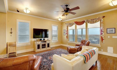 Cozy living room in a beach house at Gulf Waters Beach Front RV Resort, featuring modern furnishings, large windows with ocean views, and a warm color palette.