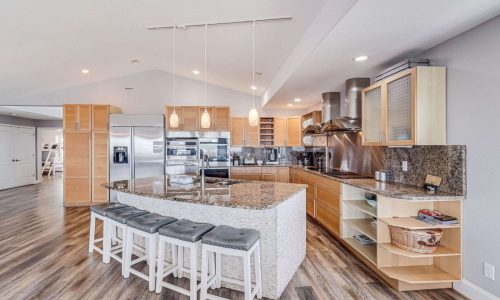 Modern kitchen interior with granite countertops, stainless steel appliances, and wooden cabinetry in a beach house at Gulf Waters Beach Front RV Resort.