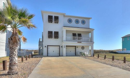 Beach house at Gulf Waters Beach Front RV Resort, featuring a modern design, palm trees, and proximity to Mustang Island's sandy shores.