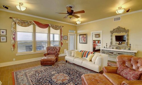 Cozy living room in a beach house at Gulf Waters Beach Front RV Resort, featuring large windows with ocean views, comfortable seating, and elegant decor.