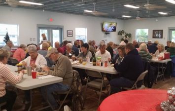 Group of guests dining together in a communal setting at Gulf Waters Beach Front RV Resort, enjoying food and conversation during a community event.