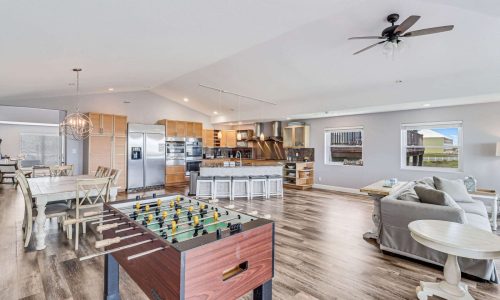 Spacious beach house interior featuring a foosball table, modern kitchen, dining area, and comfortable living space, ideal for family vacations at Gulf Waters Beach Front RV Resort.