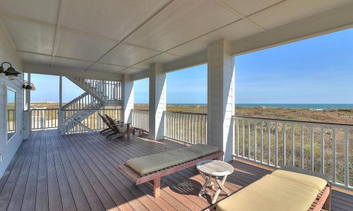 Beach house porch with seating, overlooking Mustang Island's sandy shores, ideal for relaxing during a getaway at Gulf Waters Beach Front RV Resort.
