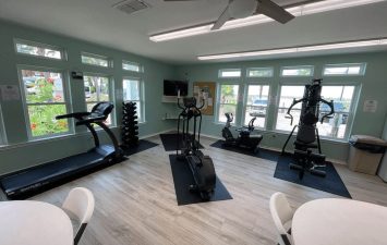 Indoor gym at Gulf Waters Beach Front RV Resort with exercise equipment and large windows.