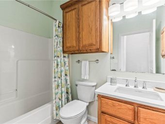 Bathroom at Gulf Waters Beach Front RV Resort with wooden cabinets and shower curtain.