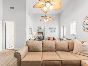 Spacious living room with beige sofa and tropical ceiling fans at Gulf Waters RV Resort.