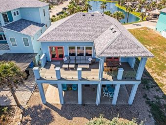 Aerial view of a beach front house at Gulf Waters RV Resort with pool and palm trees.