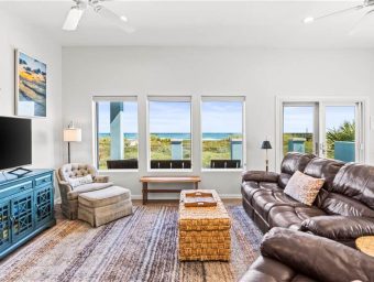 Bright living room with ocean view, leather sofa, and coastal decor at Gulf Waters Resort.