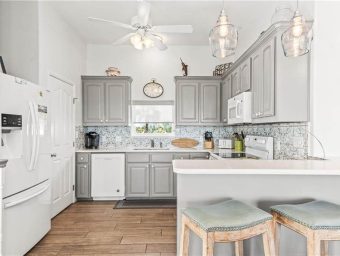 Bright modern kitchen with gray cabinets and white appliances at Gulf Waters.