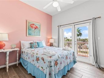 Beautiful bedroom with ocean view, pink wall, and balcony at Gulf Waters.