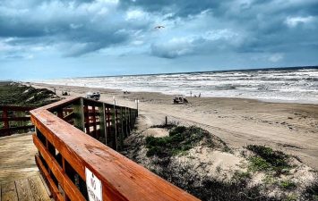 Beach view from Gulf Waters Beach Front RV Resort with ocean waves and cloudy sky.