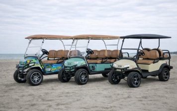 Three golf carts parked on the beach at Gulf Waters Resort.