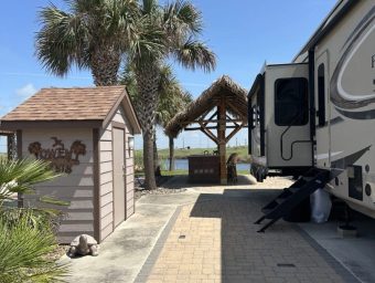 Beachfront RV site with palm trees and a thatched gazebo at Gulf Waters.