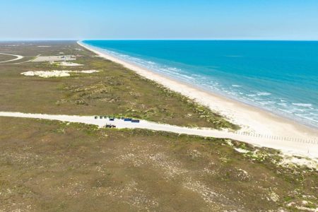 Aerial view of Padre Island National Seashore, showcasing the sandy beach, turquoise waters, and surrounding coastal vegetation, highlighting a natural attraction near Gulf Waters Beach Front RV Resort.